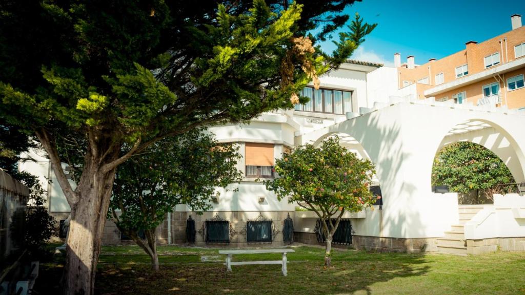 埃斯平霍Espinho Vintage - Alojamento de Charme的白色的建筑,有树和长凳