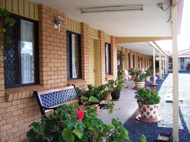 吉尔甘德拉三种方式汽车旅馆的坐在有盆栽植物的建筑旁边的长凳
