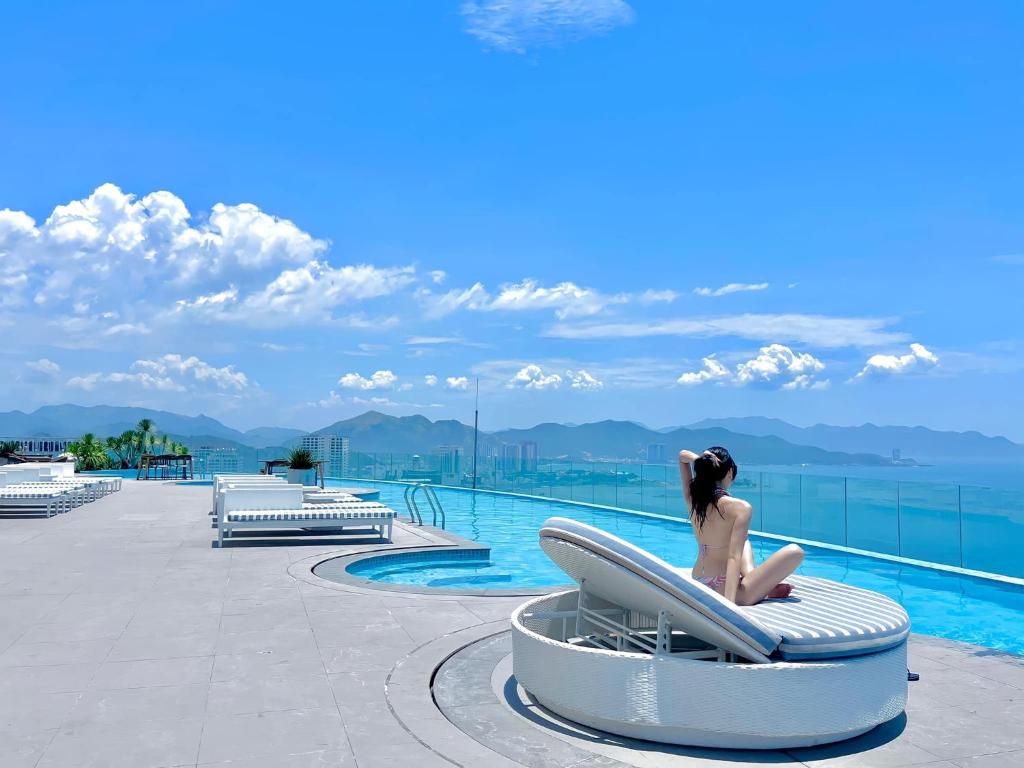 芽庄Panorama Superview Nha Trang Apartment的坐在游泳池旁椅子上的女人