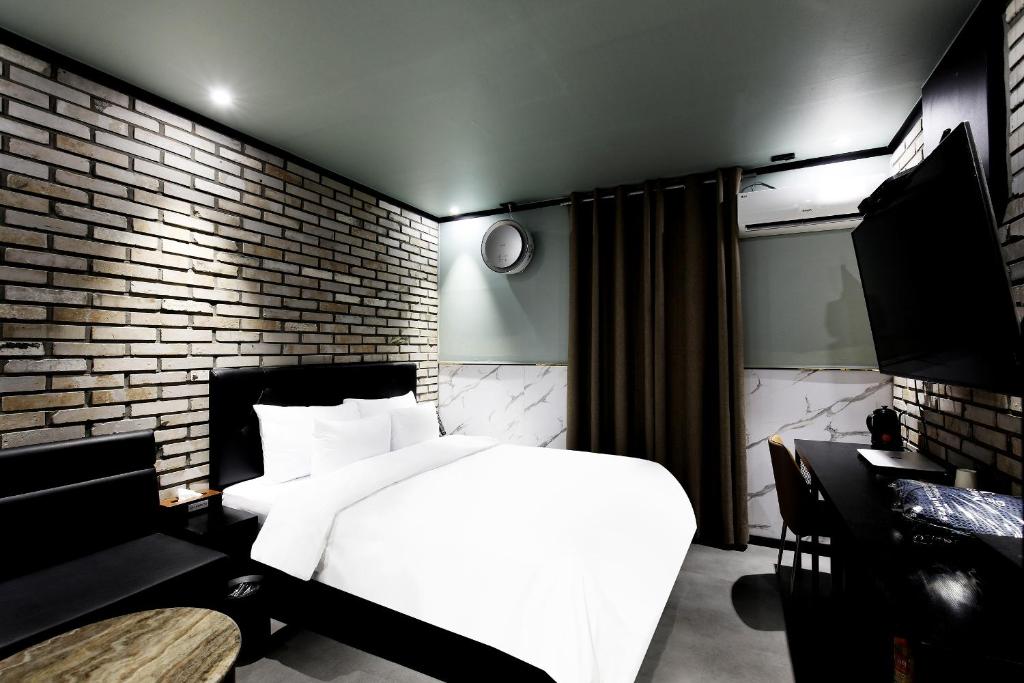 首尔Stay 25 Hotel的卧室配有白色的床和砖墙
