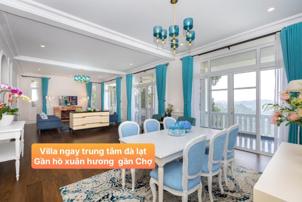 阿普春安Villa Hạng Sang Đà Lạt - Gần Hồ Xuân Hương Gần Chợ Đà Lạt的一间设有蓝色窗帘和桌椅的用餐室