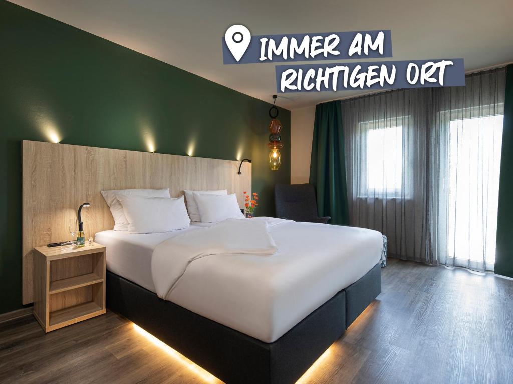 赖林根ACHAT Hotel Reilingen Walldorf的酒店客房设有一张大床和一个标志