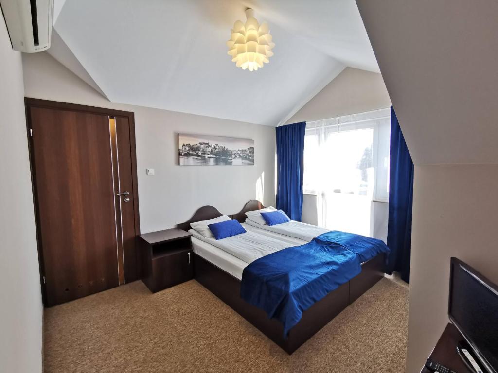 DługieSAS rooms & restaurant的一间卧室配有一张带蓝色床单和吊灯的床。