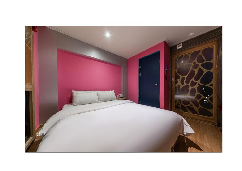 仁川市S1 Hotel的卧室配有白色的床铺和粉红色的墙壁
