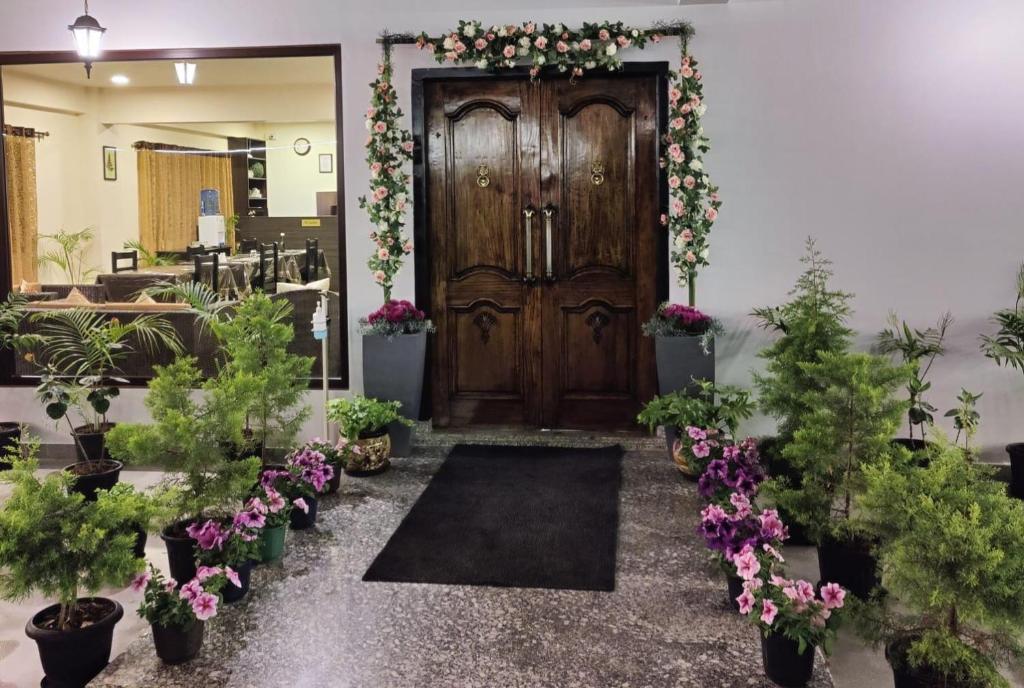 西隆The Arbour Inn的一个大木门,有植物和鲜花