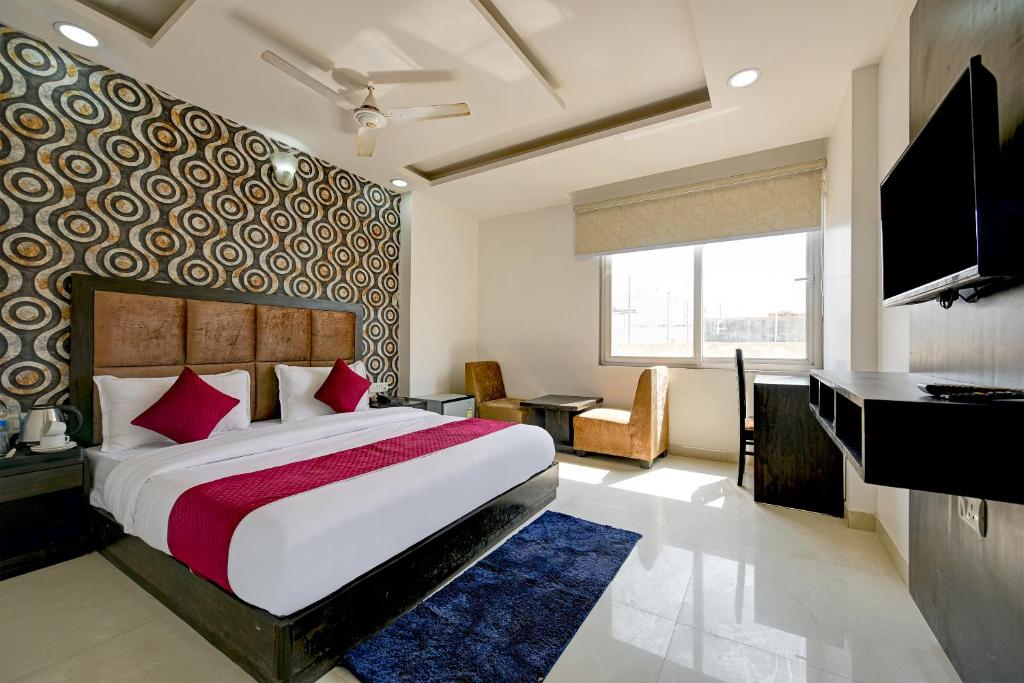 新德里Hotel Seven Inns Qubic Near Delhi Airport的一间卧室配有一张床、一张书桌和一台电视