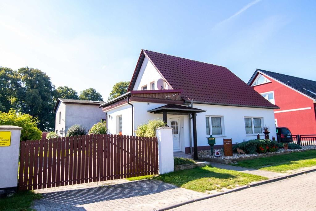 KröslinFerienhaus Geli 4的白色和红色的房子,设有木栅栏