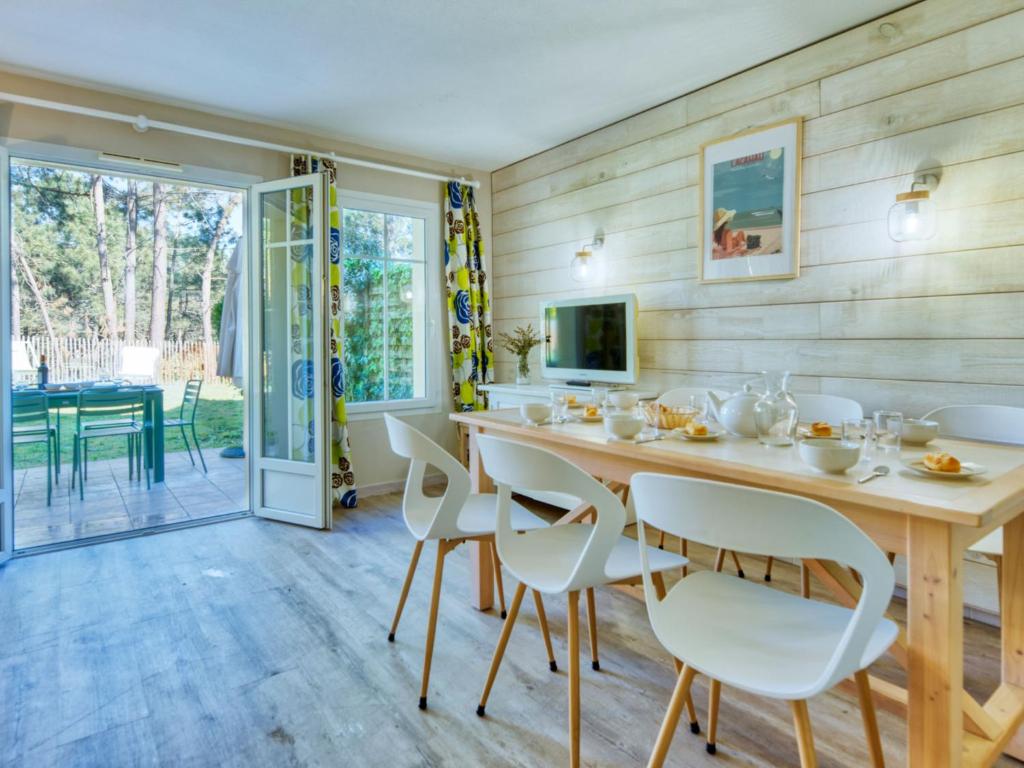 拉卡诺奥肯Holiday Home Domaine Golf Resort-2 by Interhome的一间带木桌和白色椅子的用餐室