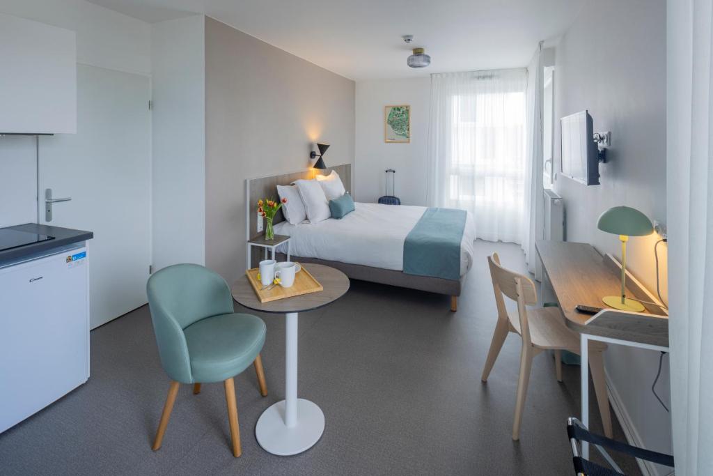 勒阿弗尔All Suites Appart Hotel Le Havre的酒店客房带一张床、一张桌子和椅子