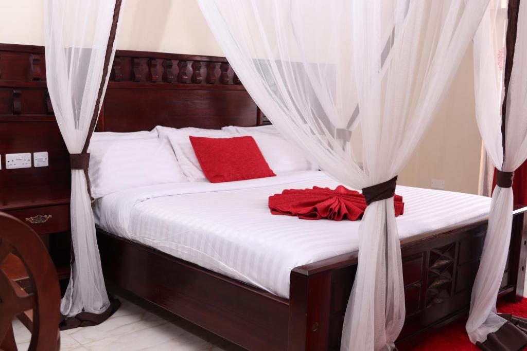 TezoWhite Peacock Resort的一张带白色床单和红色枕头的床