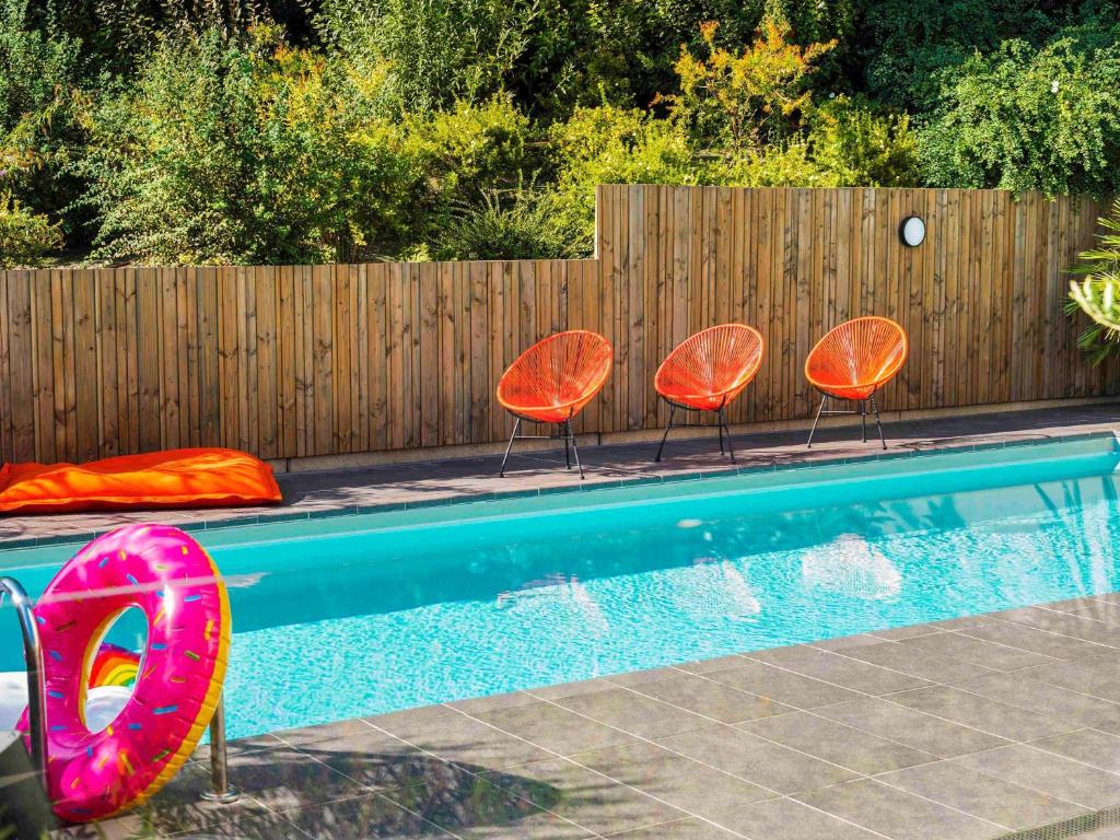 图卢兹宜必思时尚图卢兹世外桃源酒店的三把橙色椅子和一个带围栏的游泳池