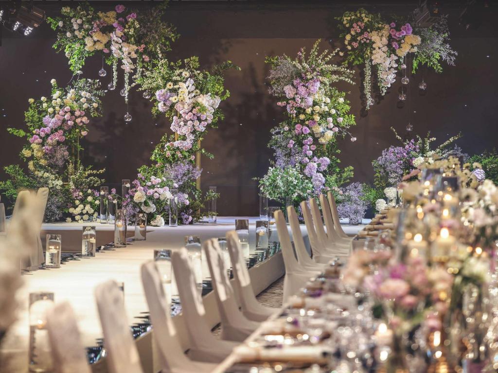 首尔诺富特大使首尔东大门酒店的一张长桌子,上面摆放着白色的椅子和鲜花