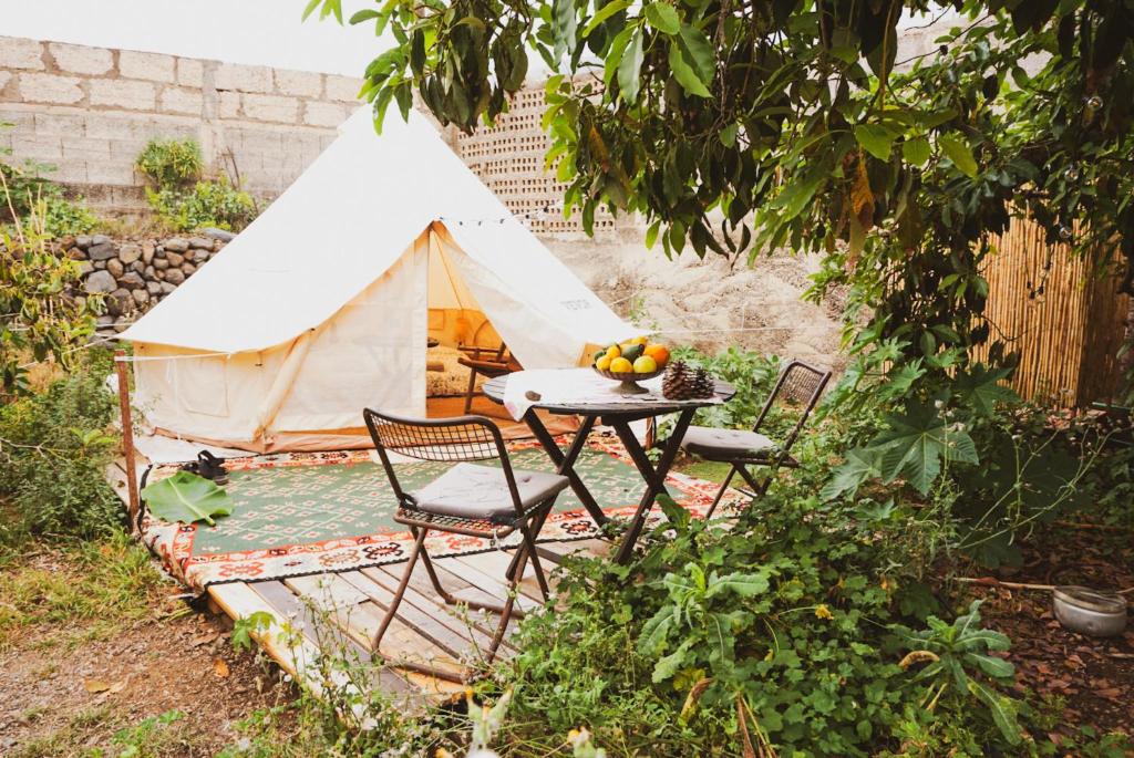 圭马尔Yurt in Avocado garden的花园内带桌椅的帐篷