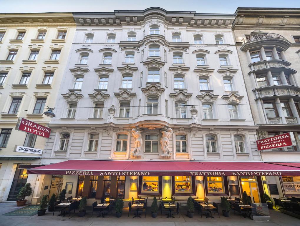 维也纳格拉本酒店的一座白色的大建筑,前面设有桌椅