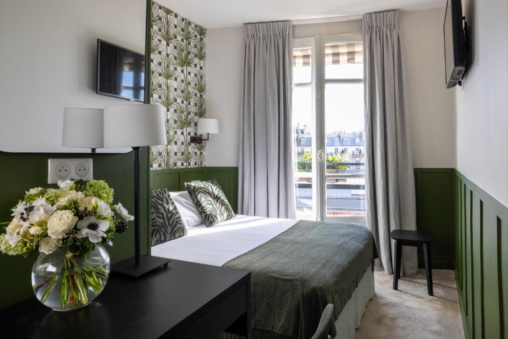 巴黎克莱门特酒店的一间卧室配有一张床和一张花瓶桌子