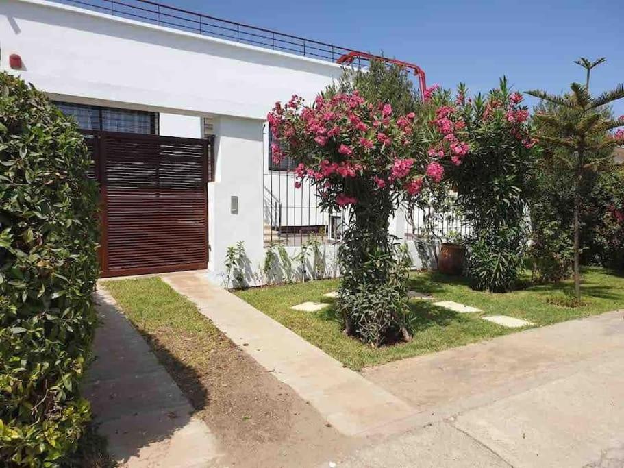 卡萨布兰卡Villa Havre De Paix à Casablanca的院子里有粉红色花的房子