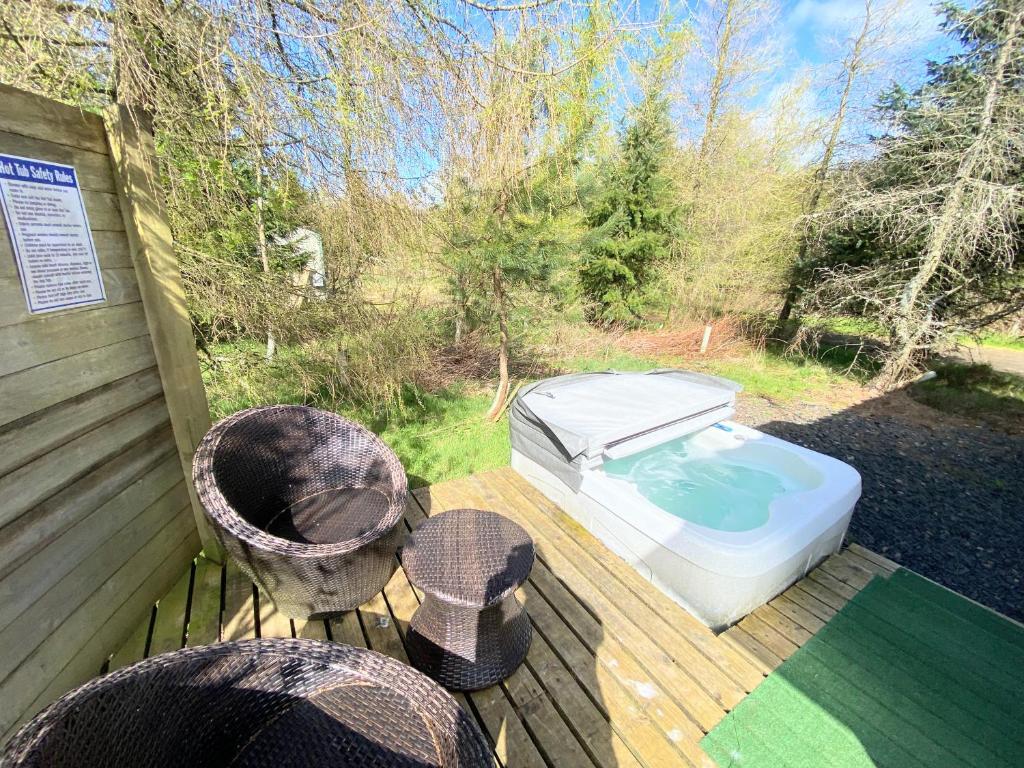 邓弗姆林Blair Tiny House with Private Hot Tub - Pet Friendly- Fife - Loch Leven - Lomond Hills的甲板上配有热水浴缸和两把椅子