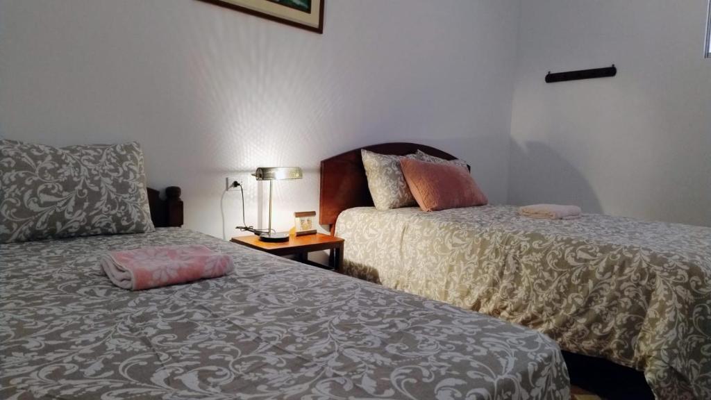 利马Hospedaje Boutique LEOS EIRL的客房设有两张床和一张带台灯的桌子。