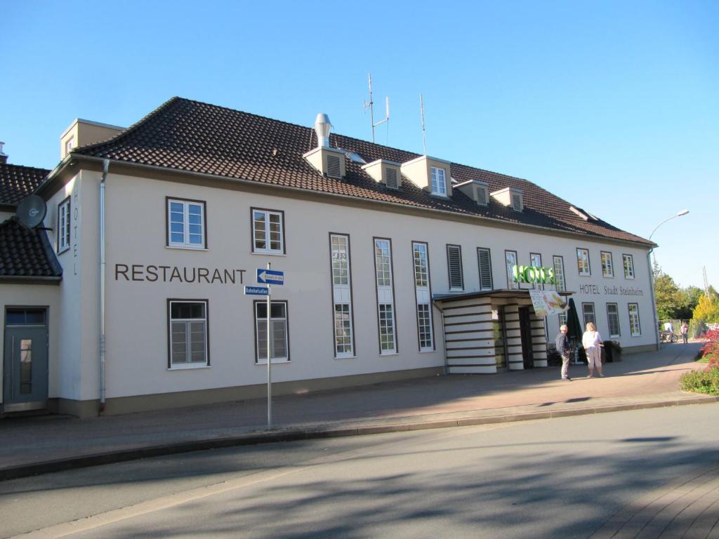 Steinheim施塔特斯德海姆酒店的一座白色的建筑,前面的人在步行