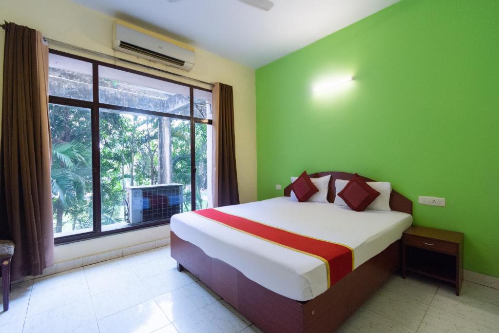 加尔各答Lake View Resort的一间卧室设有一张带绿色墙壁和窗户的床。