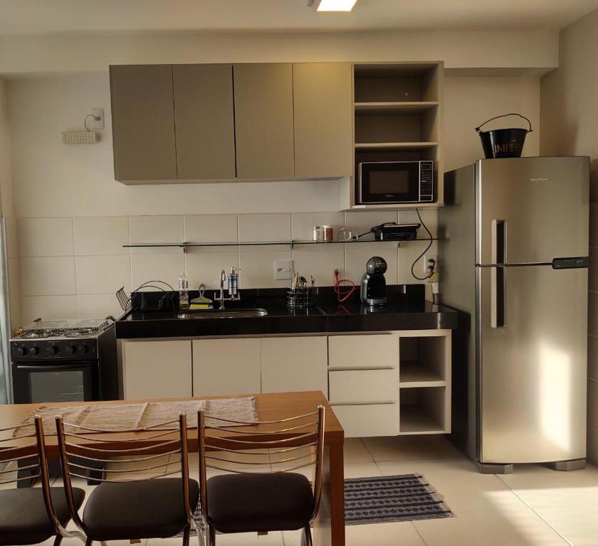 贝洛奥里藏特Apto Completo BH Arena MRV的厨房配有桌子和不锈钢冰箱。