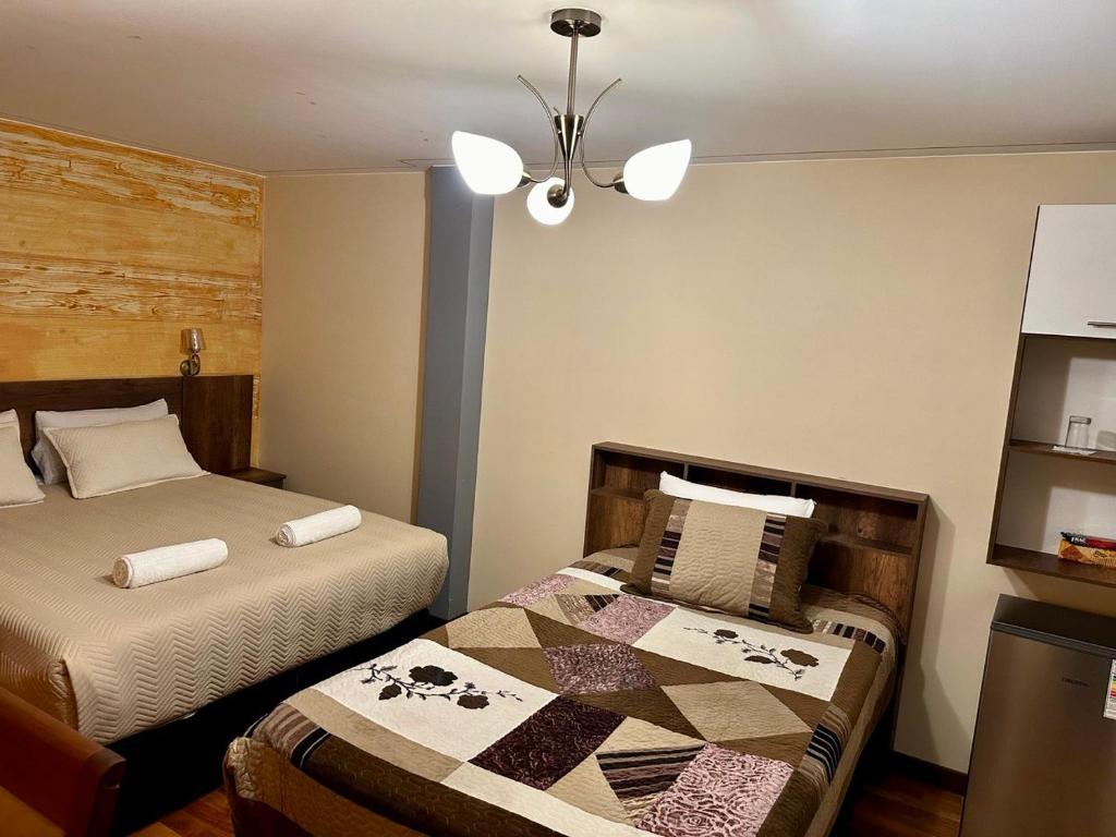 拉巴斯Hotel Esmeralda的一间卧室配有两张床和吊灯。