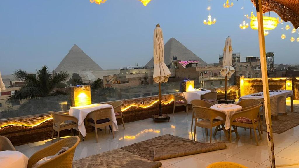 开罗Pyramids Express View HoTeL的一间设有桌椅和金字塔的餐厅