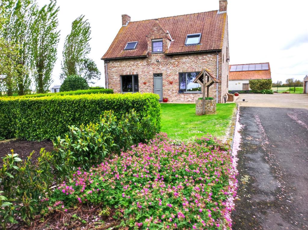 亚贝克B&B Het Polderhof的车道前方有鲜花的砖房