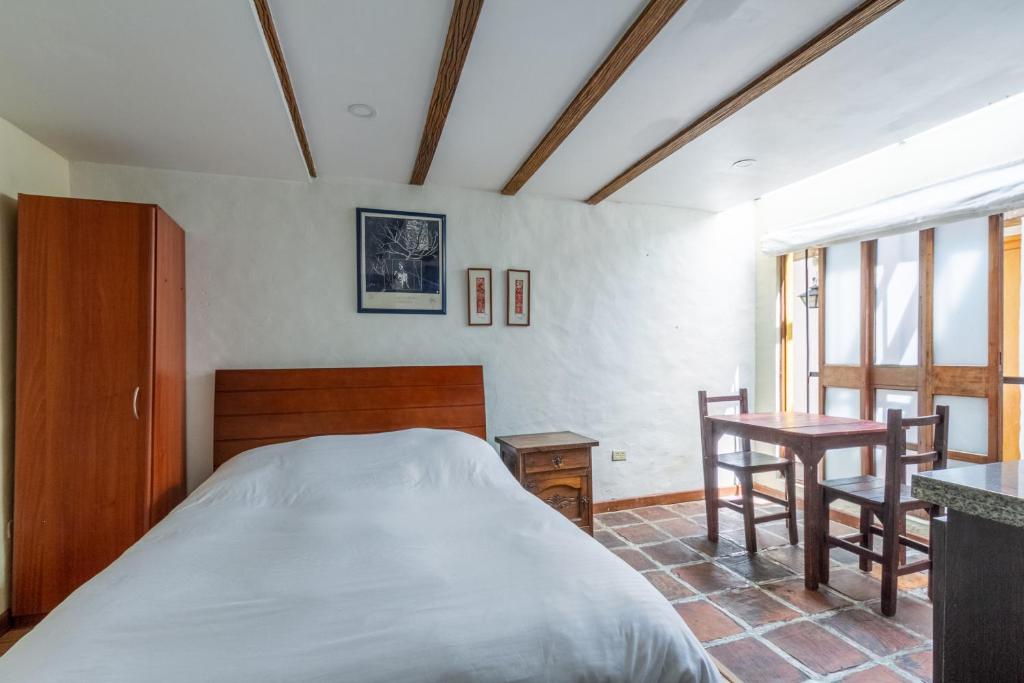 波哥大拉坎德拉里亚公寓式酒店的卧室配有一张床和一张桌子及椅子
