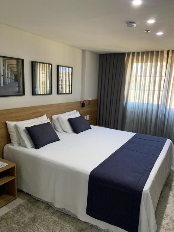 彼得罗波利斯Apartamento Hotel Itaipava Petropolis的卧室配有带蓝色枕头的大型白色床
