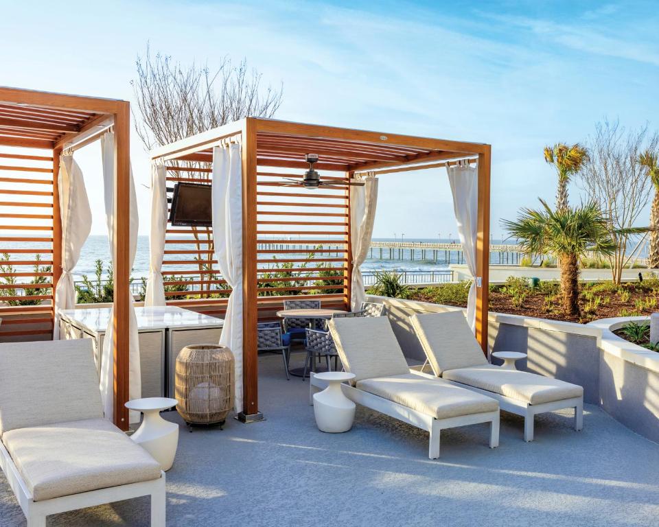 默特尔比奇Holiday Inn Club Vacations Myrtle Beach Oceanfront的庭院配有桌椅和电视。