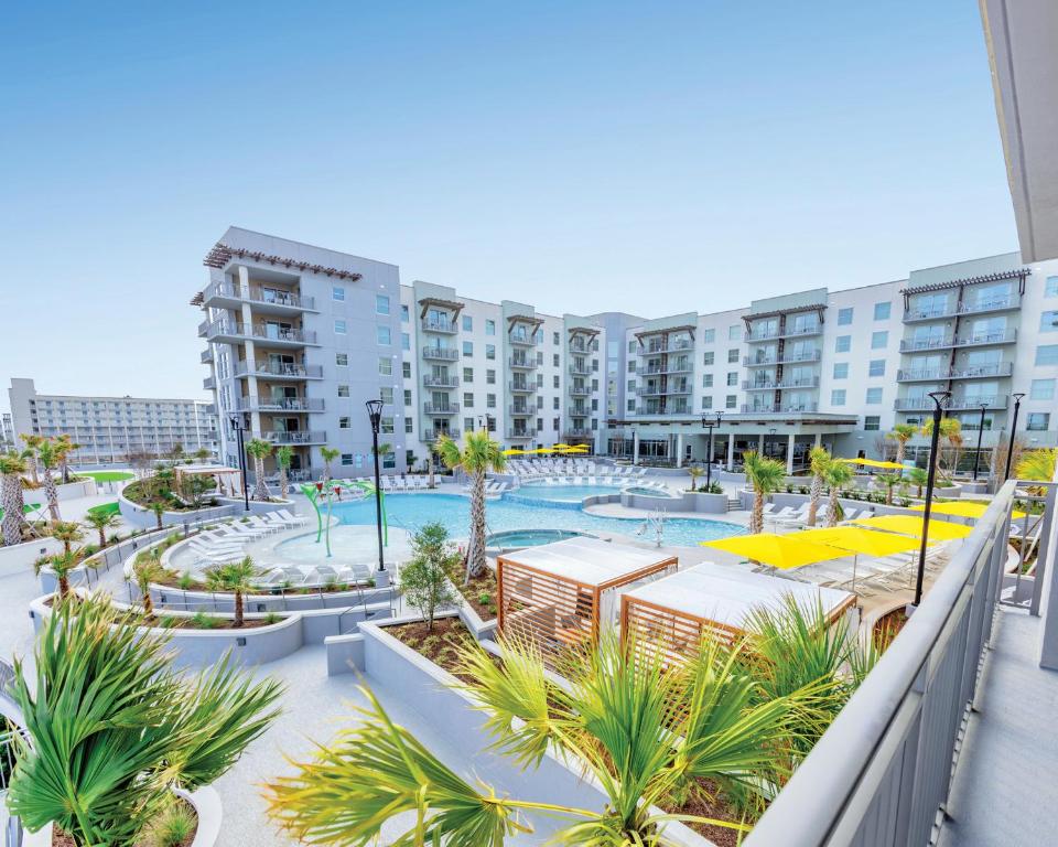 默特尔比奇Holiday Inn Club Vacations Myrtle Beach Oceanfront的公寓大楼设有游泳池和棕榈树