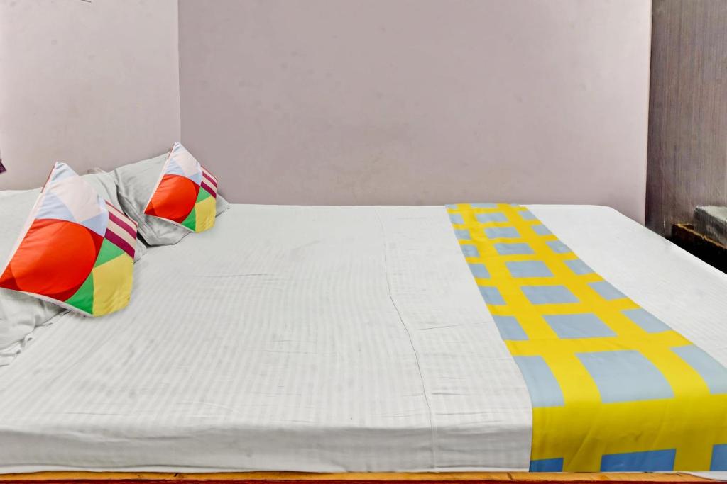 巴特那Super OYO Hotel Happy Inn的一张白色的床,上面有色彩缤纷的枕头