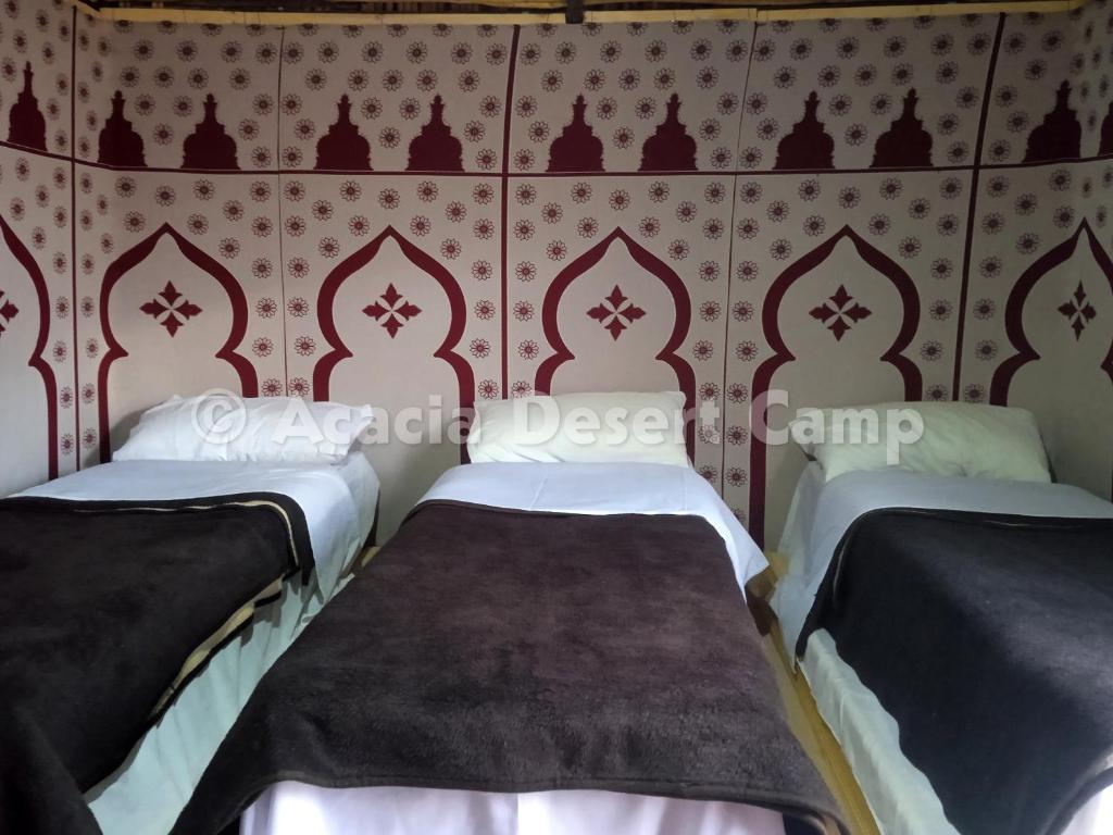 梅尔祖卡Acacia Desert Camp的红色和白色壁纸客房内的两张床