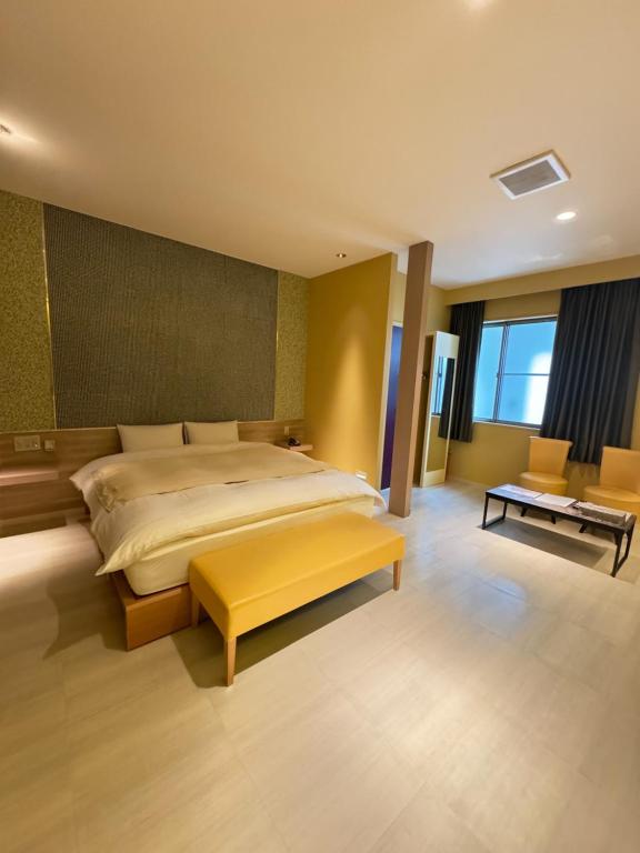 Saijō-chōHotel JOYCE的一间卧室设有一张大床和一张黄色长凳