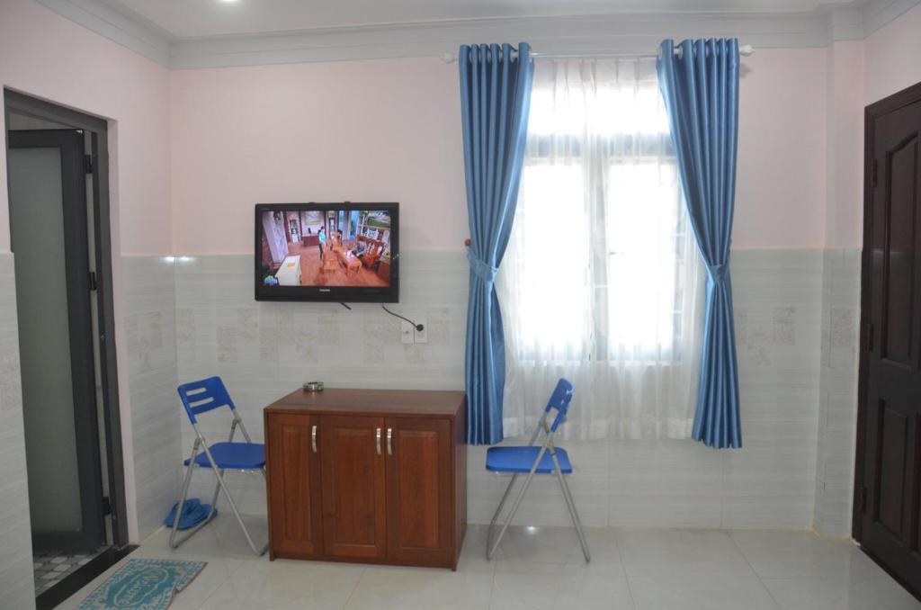 Dĩ Anhotel Hương Thiên Phú的一间设有两把椅子、一张桌子和一台电视的房间