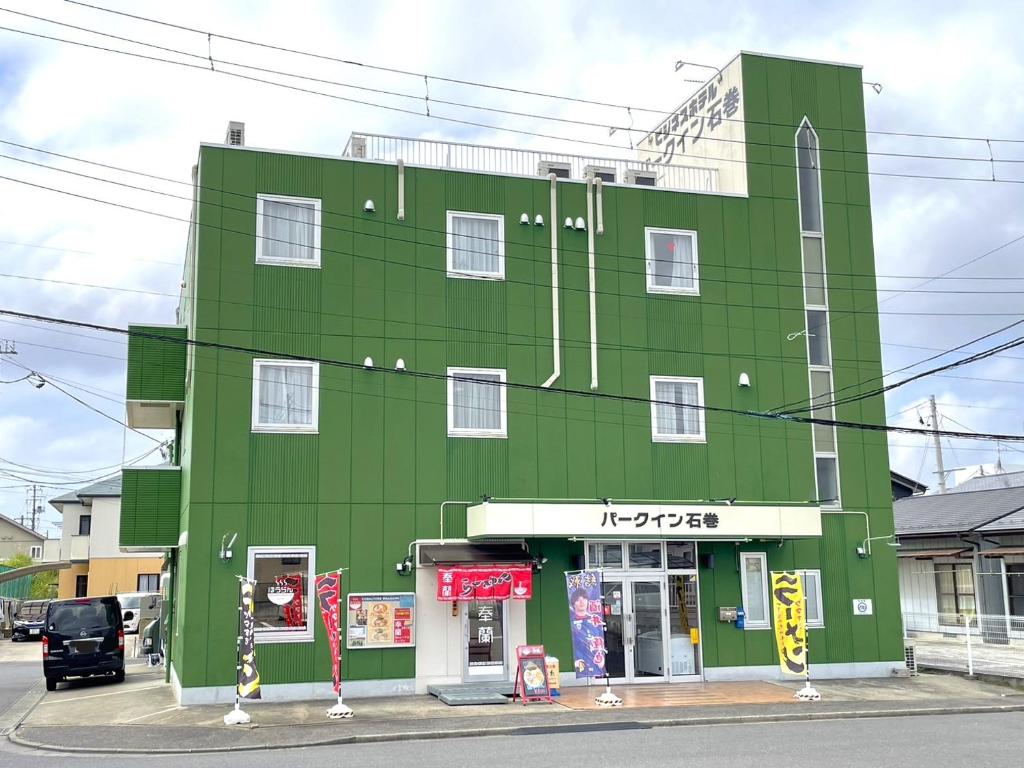 Inaiビジネスホテルパークイン石巻的街道拐角处的绿色建筑