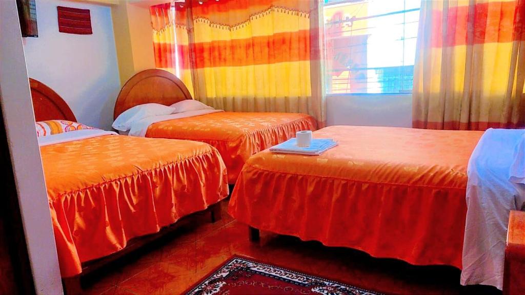 普诺HOSTAL ACUARIUS PUNO的客房 - 带两张带橙色床单的床