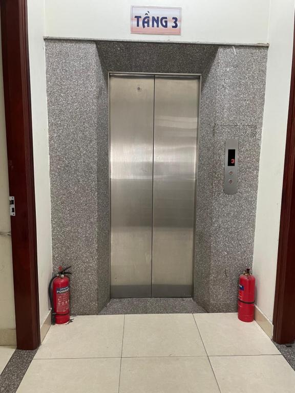 海阳Trúc Lâm hotel的两扇红色灭火器的建筑物中的金属电梯