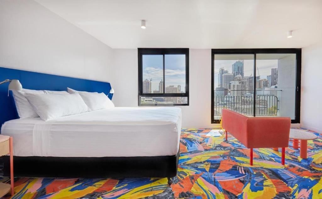 悉尼Adge Hotel and Residence - Adge King - Australia的一间卧室配有一张大床和一张红色椅子