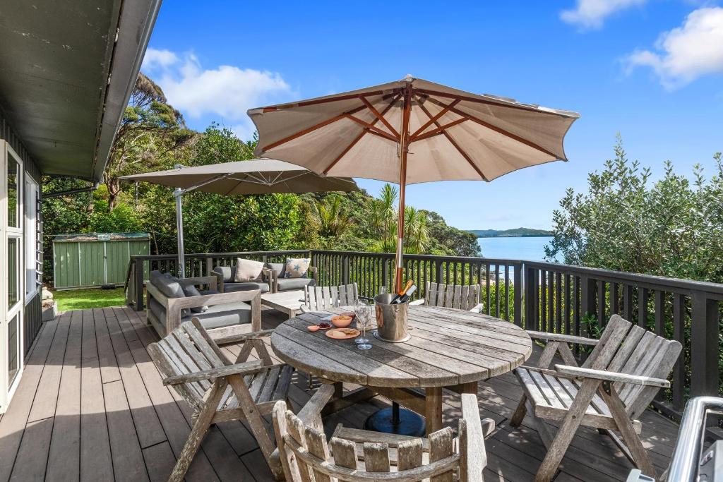 旺阿雷Kereru Cottage - Matapouri Holiday Home的甲板上配有一张木桌和椅子及遮阳伞