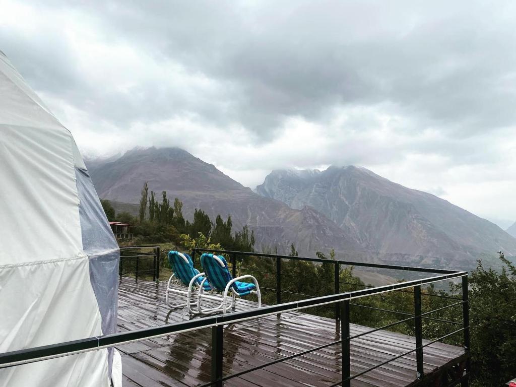 罕萨Glamping Resort Hunza的两把椅子放在一个甲板上,甲板上享有山景