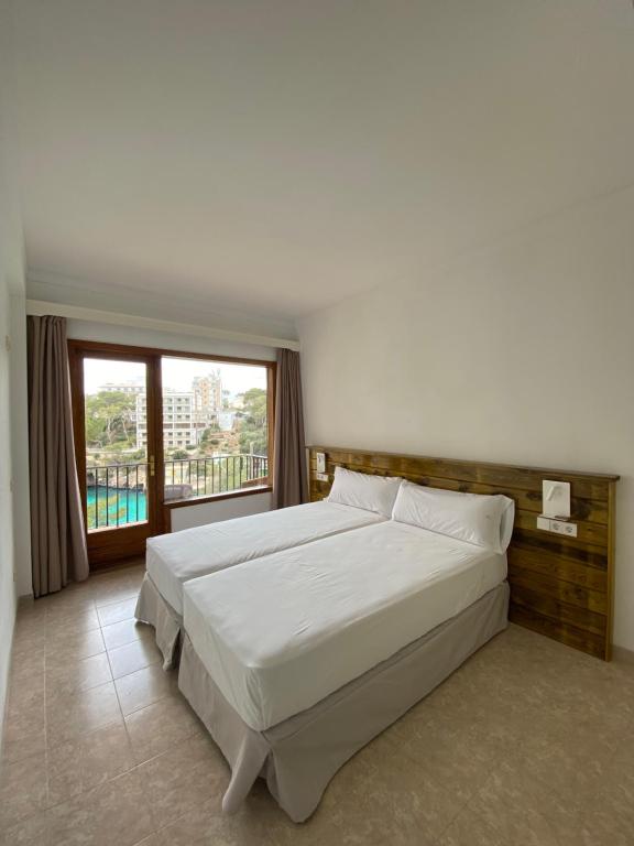 卡拉桑塔尼Hostal Palmaria的一间卧室设有一张大床和一个大窗户