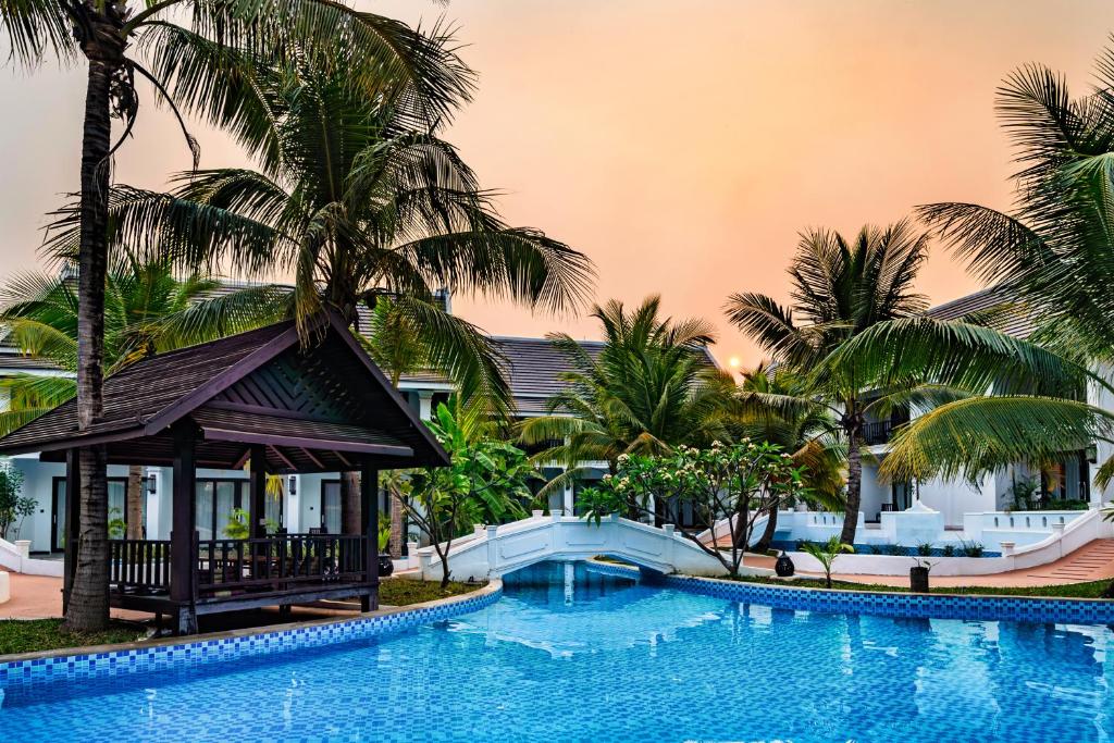 琅勃拉邦Manyo Hotel and Resort的棕榈树度假村前的游泳池
