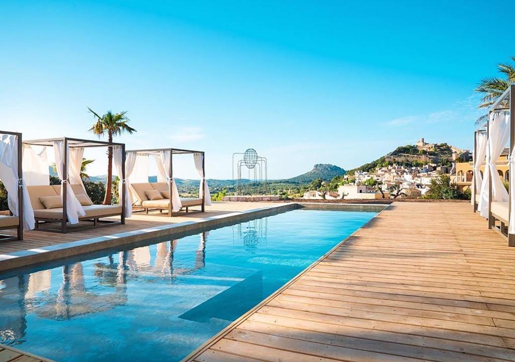 卡普德佩拉Hotel Creu de Tau Art&Spa-Adults only的一个带椅子和棕榈树的度假村游泳池