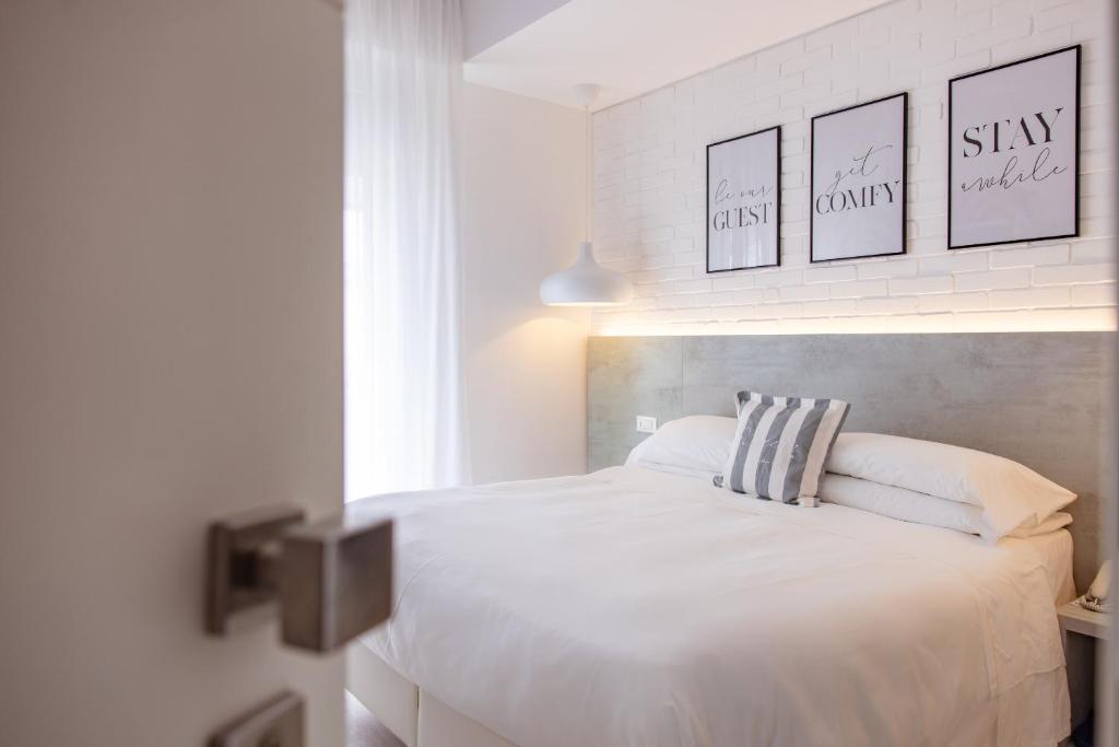 卡托利卡Hotel Gambrinus Mare的卧室配有一张白色床,墙上挂有三张照片