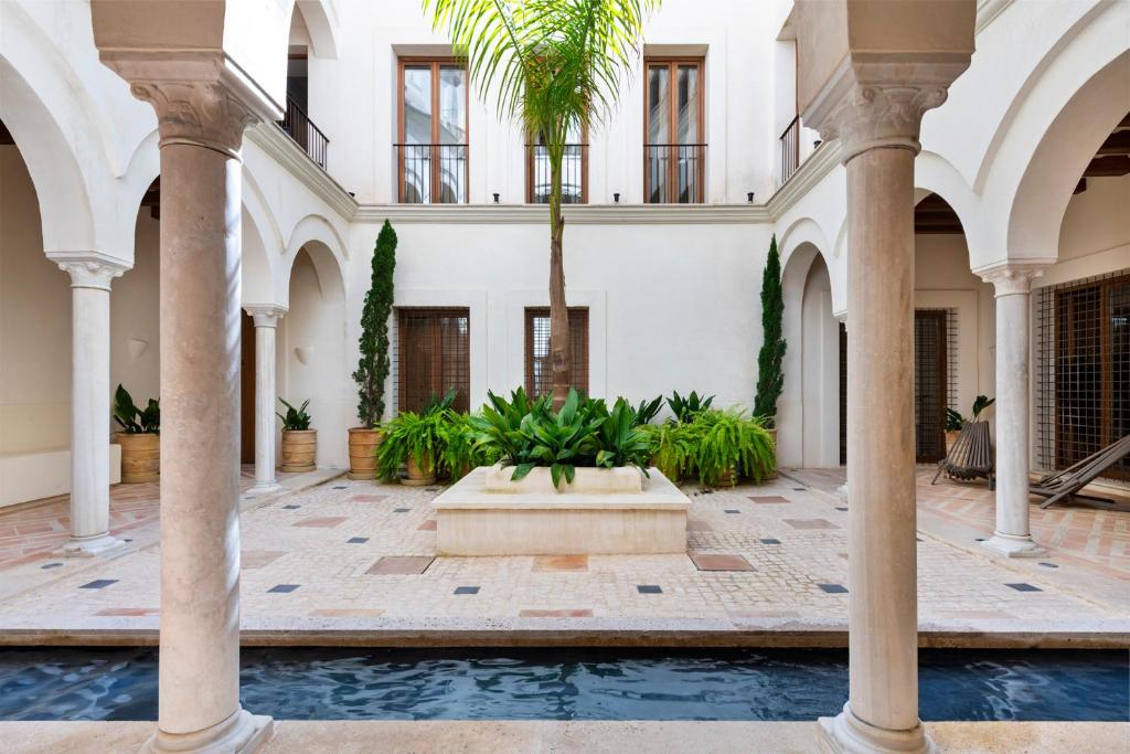 塞维利亚Casa del Rey Sabio的一个带棕榈树和喷泉的庭院