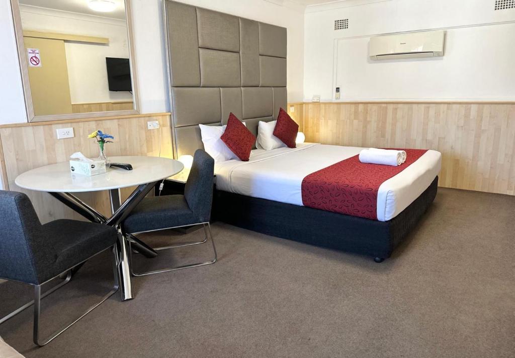 考拉考兰乡村人汽车旅馆的一间卧室配有一张床和一张桌子及椅子
