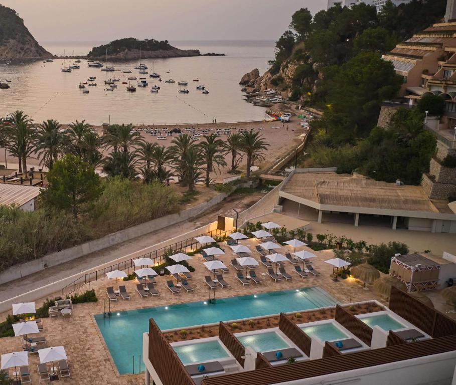 圣米格尔港The Club Cala San Miguel Hotel Ibiza, Curio Collection by Hilton, Adults only的享有带游泳池和海滩的度假村的空中景致