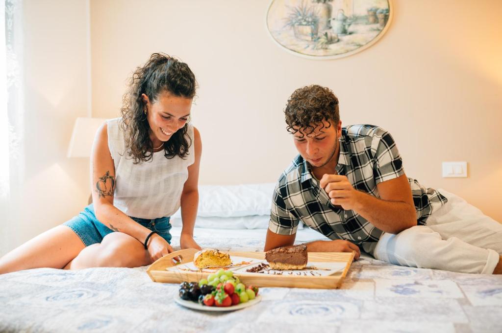 托莱港Hotel Ponte Molo的坐在床上的男人和女人,有盘子的食物